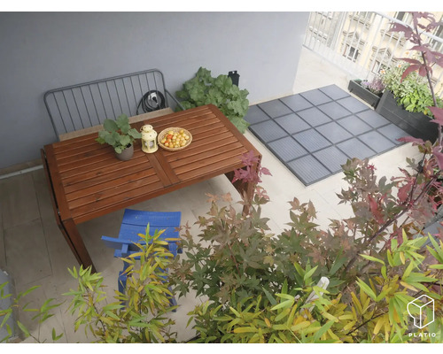 Dekorierter Balkon mit Holztisch, Stuhl, Pflanzen und Bodenplatten