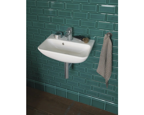 Badezimmerwaschbecken mit Armatur und Handtuch vor Fliesenwand