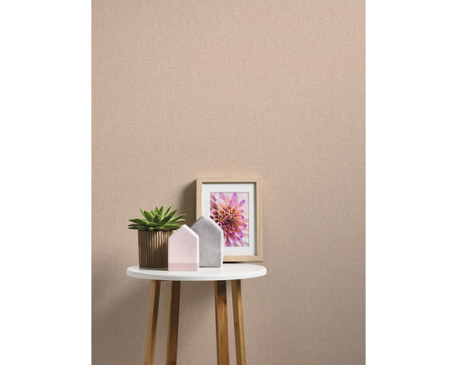 Dekoratives Stillleben mit einer Pflanze, zwei Dekohäusern und einem gerahmten Bild auf einem kleinen Tisch vor einer einfarbigen Wand