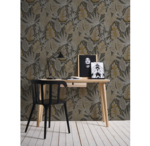 Raumansicht mit Schreibtisch, Stuhl, Lampe und gemusterter Tapete mit Blattmotiven
