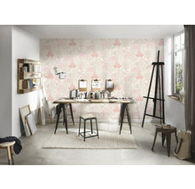 Ein helles Atelier mit einer gemusterten Tapete, einem Holztisch und verschiedenen Künstlerutensilien.