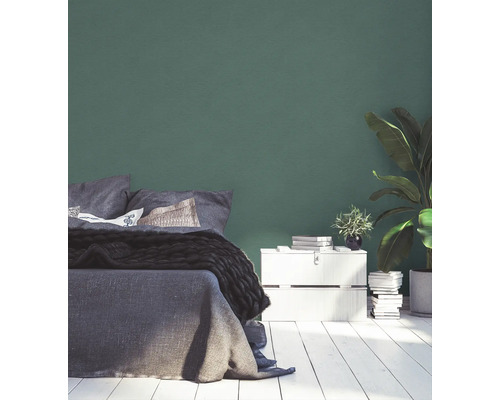 Chambre à coucher avec lit, table de chevet et plante d''intérieur devant un mur vert