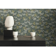 Dekoratives Zimmer mit Blumentapete, Skulptur und Zimmerpflanze auf einem Tisch