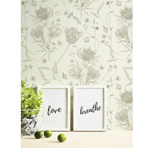 Szene mit Blumentapete, zwei gerahmten Postern mit den Aufschriften Liebe und Atmen, Topfpflanze und Limetten