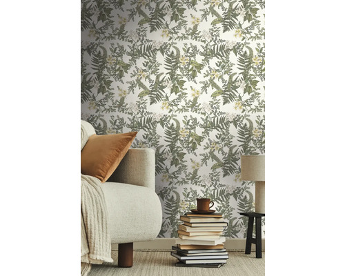 Wohnzimmer mit floral gemusterter Tapete, Sofa, Büchern und Lampe