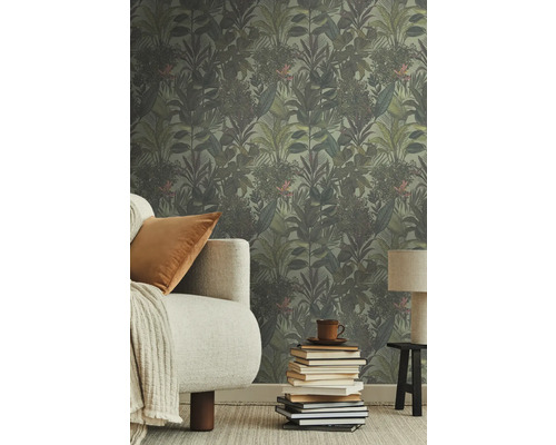 Pièce avec papier peint jungle, canapé, coussin, lampe et pile de livres.