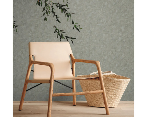 Fauteuil clair en bois et cuir à côté d''un panier devant un mur avec des plantes