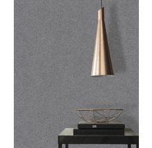 Gros plan d''un papier peint gris avec une structure fine dans une pièce avec une lampe et des objets décoratifs.