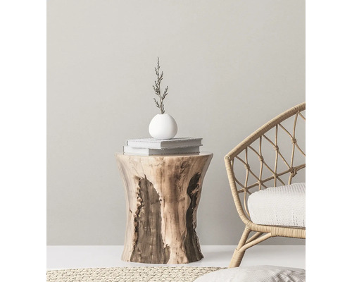 Dekoratives Interieur mit einem Beistelltisch aus Holz, Büchern, einer Vase und einem Korbstuhl.