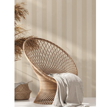 Dekorative Szene mit Rattan-Sessel, Decke und Korb vor gestreifter Wand