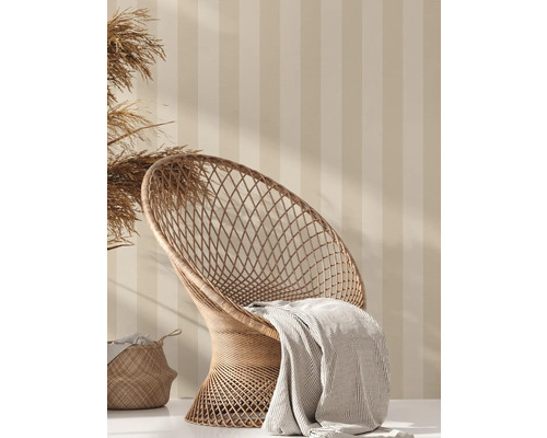 Dekorative Szene mit Rattan-Sessel, Decke und Korb vor gestreifter Wand