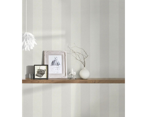 Innenaufnahme eines Raumes mit gestreifter Tapete, dekoriert mit einer Holzablage, Fotorahmen und einer Lampe