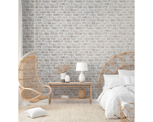 Chambre lumineuse avec papier peint imitation briques, fauteuil suspendu et lit en rotin