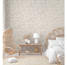 Helles Schlafzimmer mit Backsteintapete, Rattansessel und Bett