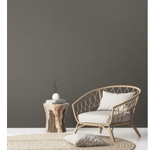 Dekorative Szene mit Rattan Sessel, Holzhocker, Teppich und Kissen für eine gemütliche Atmosphäre