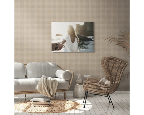 Wohnzimmer mit Sofa, Sessel und einem Wandbild mit Strandmotiv