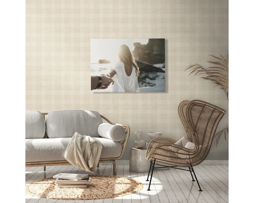 Wohnzimmer mit Sofa, Rattansessel und Wandbild mit Strandmotiv