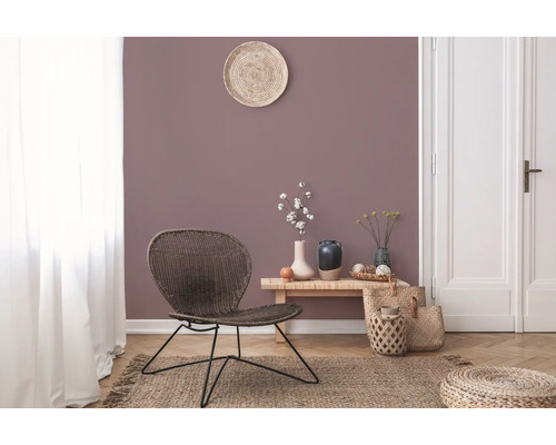 Wohnzimmer mit Rattansessel, Holztisch und Dekorationen auf einem Teppich