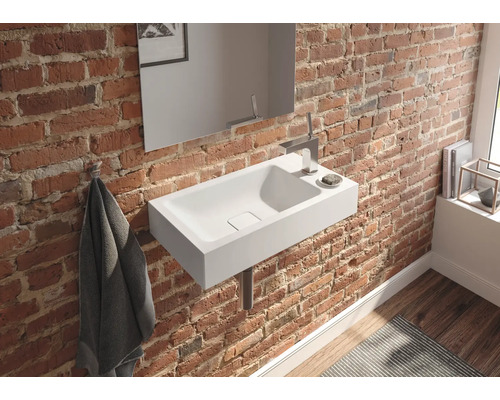 Salle de bains avec lavabo, miroir et serviette sur un mur de briques