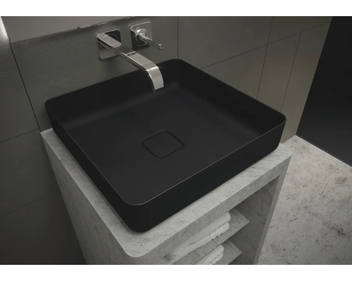 Vasque à poser noire sur meuble-lavabo avec étagères et serviettes.