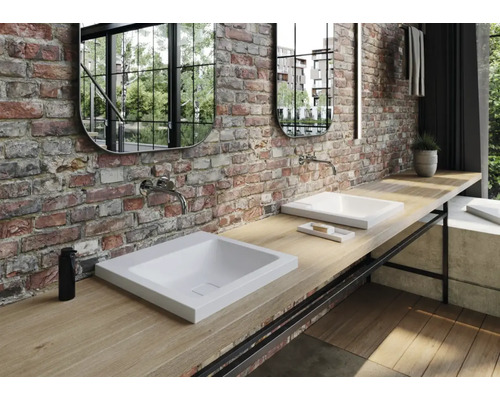 Salle de bains avec lavabos, robinets, miroirs et plan de travail en bois contre mur de briques