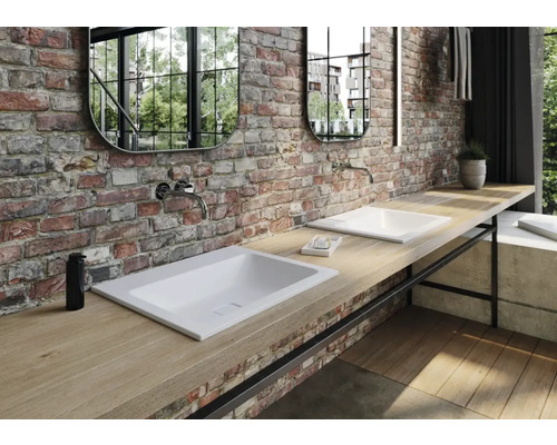 Salle de bains avec deux vasques à poser sur un plateau en bois devant un mur en briques