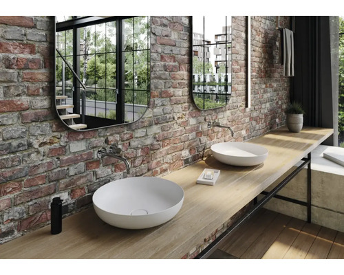 Salle de bains avec deux vasques à poser, deux miroirs et un mur en briques.