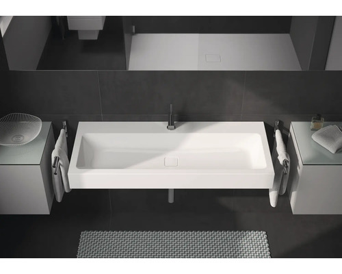 Salle de bain moderne avec lavabo rectangulaire, robinetterie et surfaces de rangement.