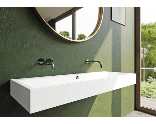 Badezimmer mit einem länglichen, wandhängenden Waschbecken, Armaturen und einem runden Spiegel