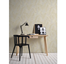 Scène avec un bureau, une chaise, une lampe et un papier peint à motif de feuilles.