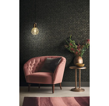 Wohnzimmer mit Sessel, Kissen, Beistelltisch, Lampe und gemusterter Tapete.