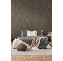 Schlafzimmer mit gemusterter Tapete, Bett, Hocker und Teppich für ein gemütliches Ambiente.