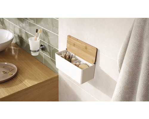 Scène de salle de bains avec un lavabo, un porte-gobelet pour brosses à dents et une étagère murale avec couvercle en bambou pour ranger les accessoires de salle de bains.
