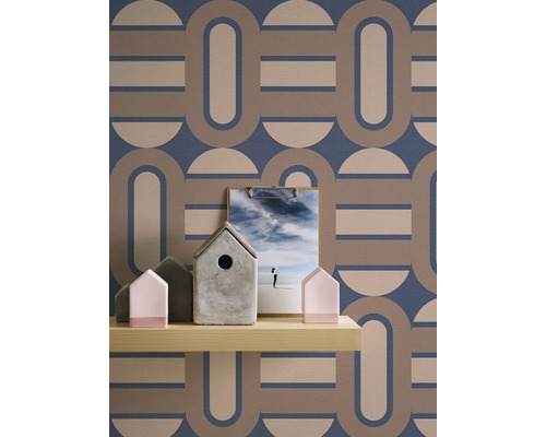 Étagère avec maisons décoratives et presse-papiers devant un papier peint rétro