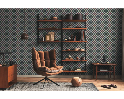 Salon avec papier peint à motifs, étagères, fauteuil, tapis et plancher en bois.