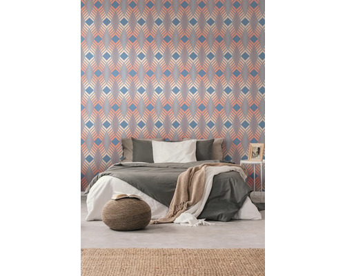 Chambre à coucher avec papier peint à motifs, lit et tapis pour une atmosphère chaleureuse.