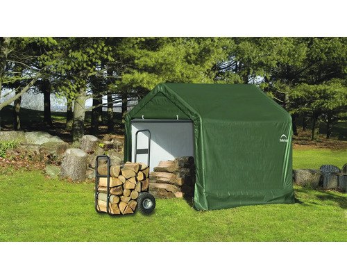 Abri de jardin vert avec bois de chauffage et chariot dans le jardin.