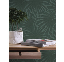 Dekorative Wand mit Palmenmuster, Tisch mit Pflanze und Büchern