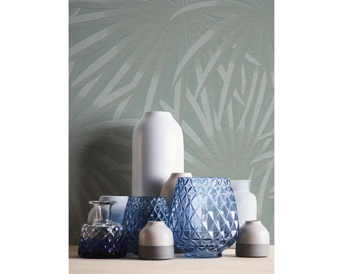 Verschiedene Vasen vor einer Wand mit Blattmuster.