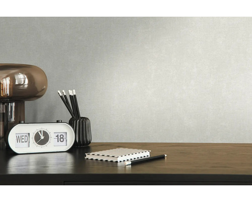 Nahaufnahme eines Schreibtischs mit Schreibtischlampe, Tischkalender, Notizblock, Stifthalter und Stiften vor einer strukturierten Wand.