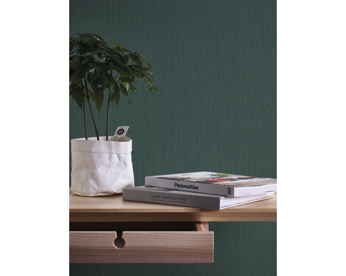 Gros plan d''une pièce avec du papier peint vert, une table en bois, des livres et une plante d''intérieur.