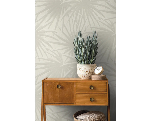 Pièce avec papier peint à motifs, commode, plante en pot et objets de décoration.