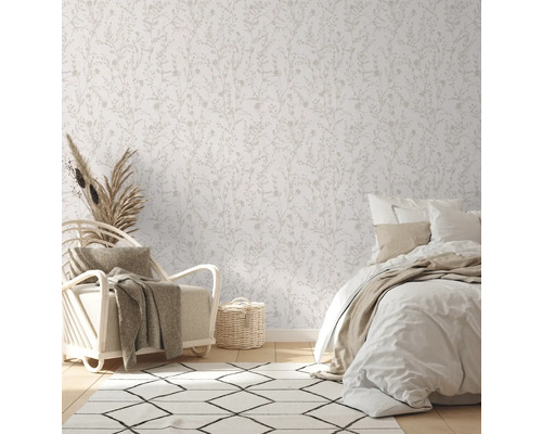 Helles Schlafzimmer mit floral gemusterter Tapete, Sessel und Bett