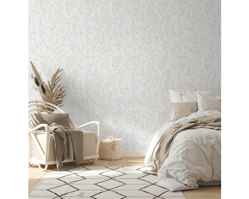 Chambre lumineuse avec papier peint à motifs floraux, fauteuil et lit.