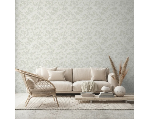 Wohnraum mit Couch, Sessel, Tisch und floral gemusterter Tapete.