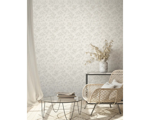 Wohnzimmer mit floral gemusterter Tapete, Rattansessel und Couchtisch