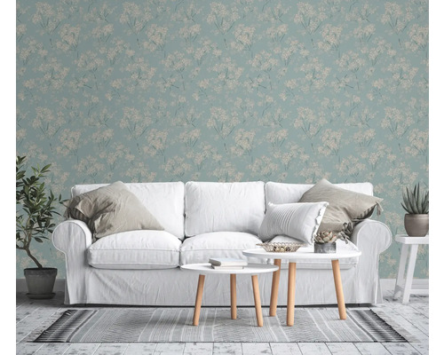 Salon avec papier peint à motifs floraux, canapé blanc et tables basses.