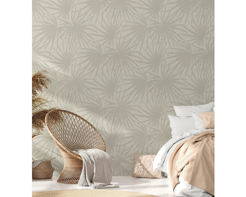 Chambre avec papier peint à motifs, fauteuil en rotin et lit