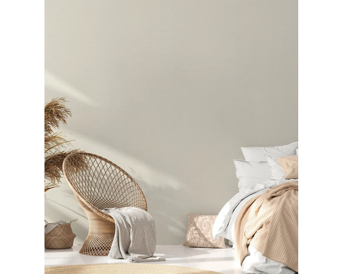 Espace de couchage lumineux avec chaise en rotin et lit double.