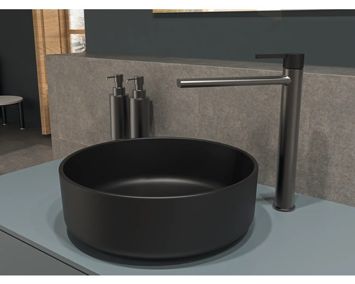 Vasque noire avec robinet et deux distributeurs de savon dans la salle de bain